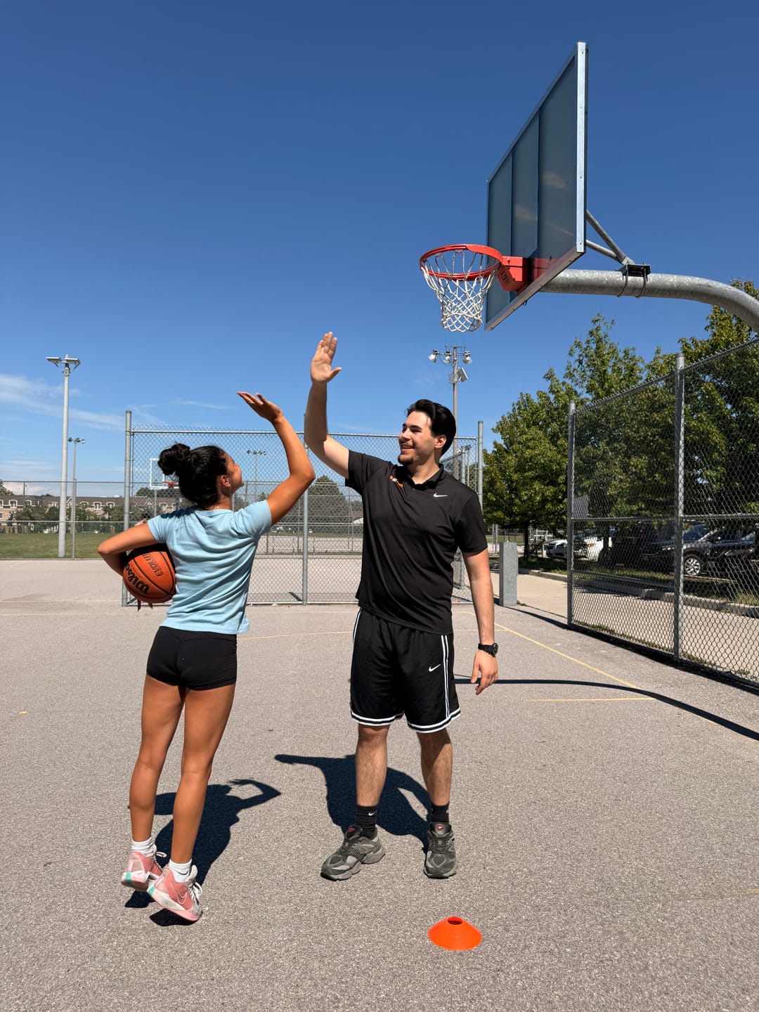 URAZ HOOPS coach and player sharing a high-five during an outdoor training session in Vaughan