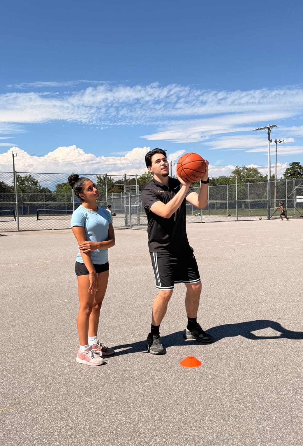 URAZ HOOPS coach breaking down shooting form for a player on an outdoor court in Vaughan