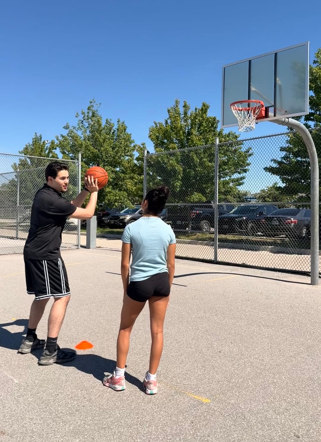 URAZ HOOPS coach demonstrating shooting technique to a player on a Vaughan court