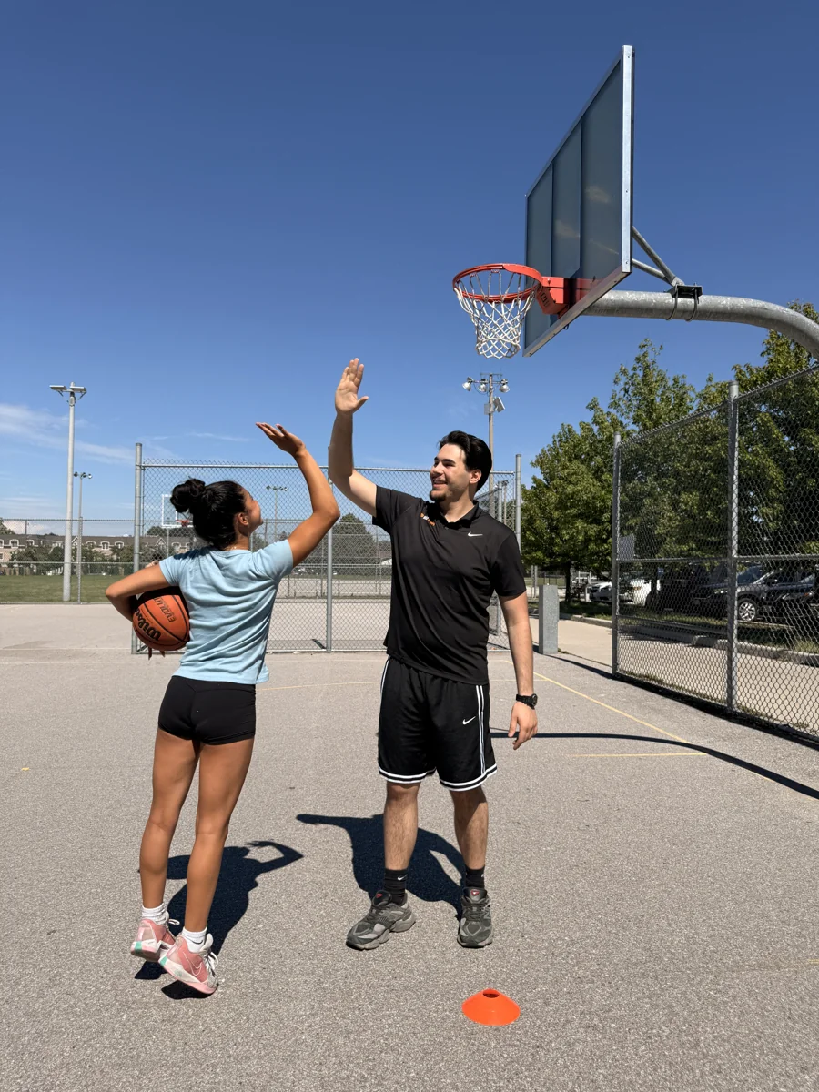 Mert Uraz sharing a high-five with a young player after an outdoor drill