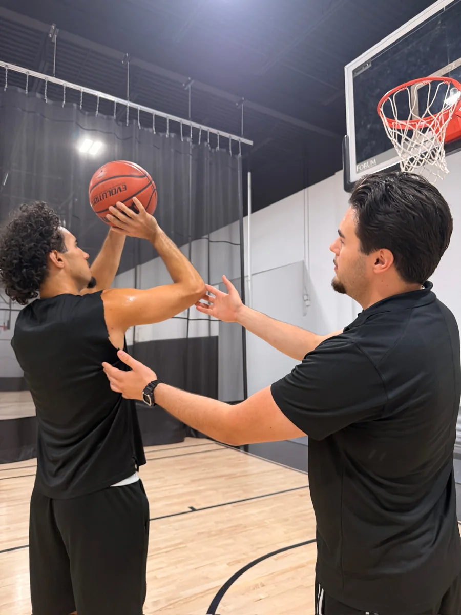 Mert Uraz giving feedback on a player’s shooting form indoors