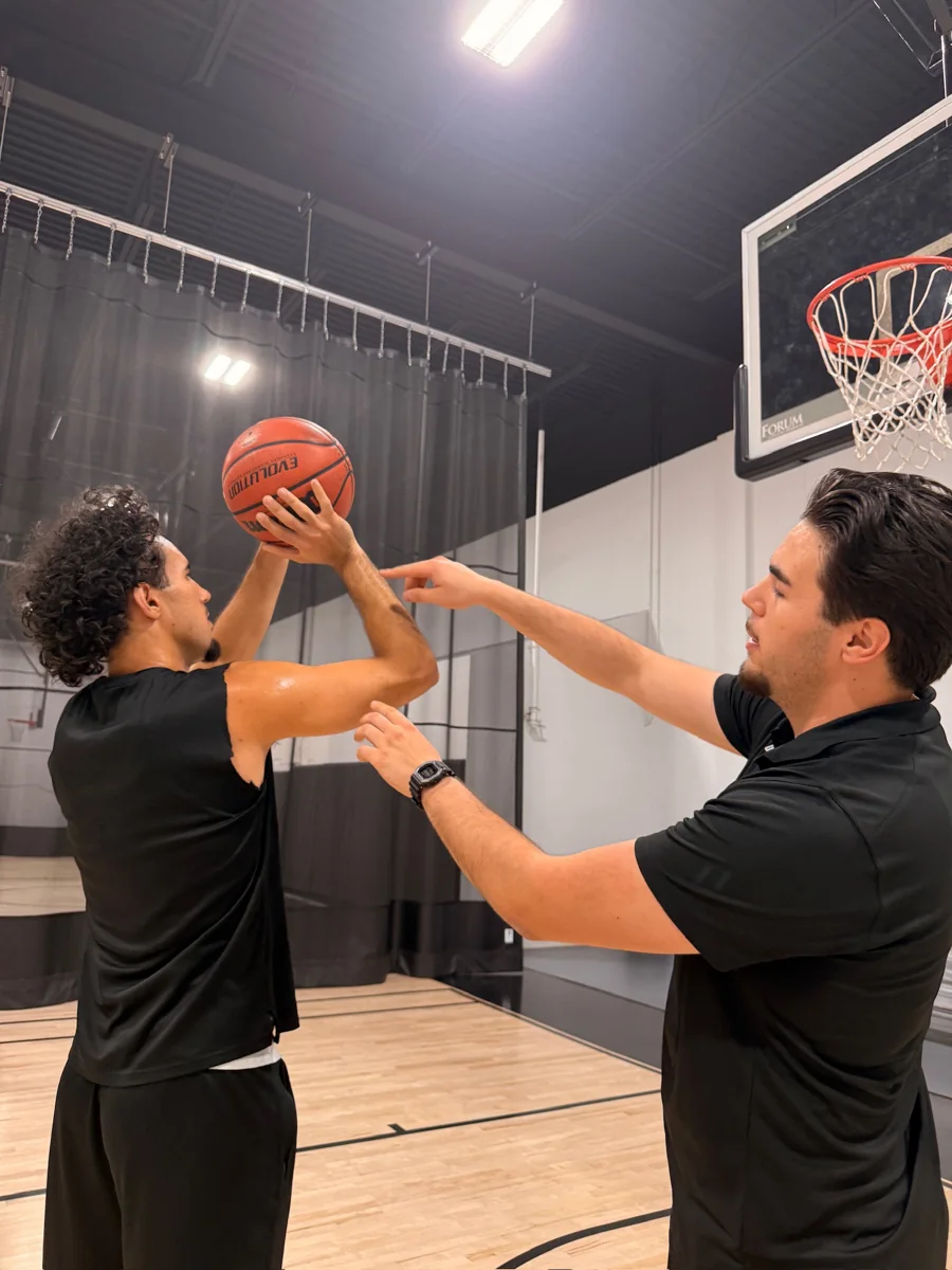 Mert Uraz guiding a player’s shooting form on an indoor basketball court