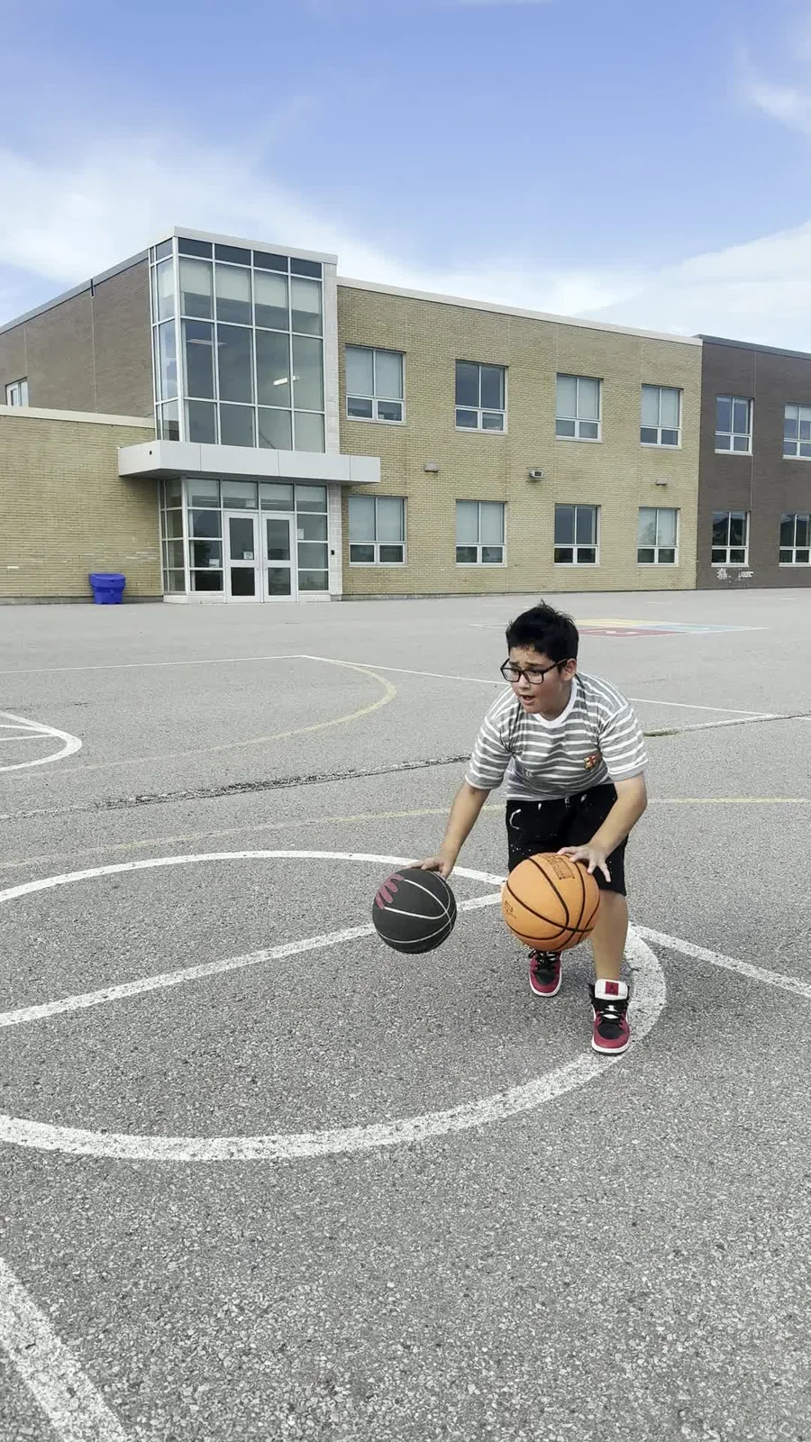A young player practising a two-ball handling drill on an outdoor court